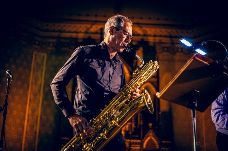 Solo de sax barítono diante de parede dourada