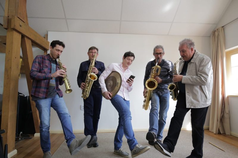 O quinteto tocando e dançando num estúdio