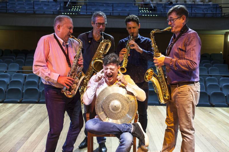 Integrantes em momento descontraído no palco de um teatro
