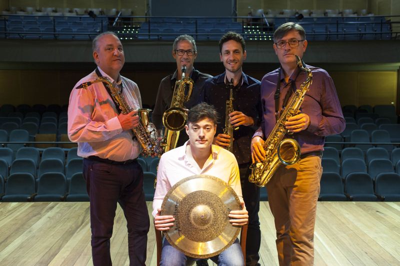 O grupo no palco de um teatro, em clima descontraído