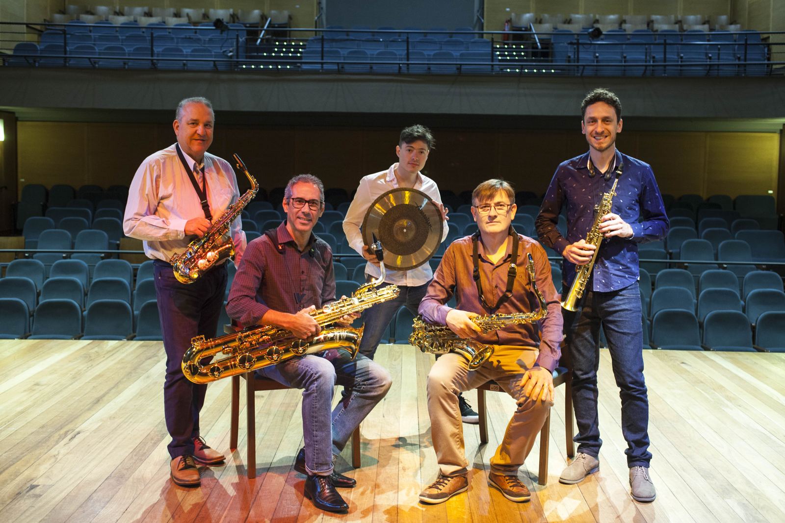 Os cinco integrantes do Barlavento no palco de um teatro, com seus instrumentos